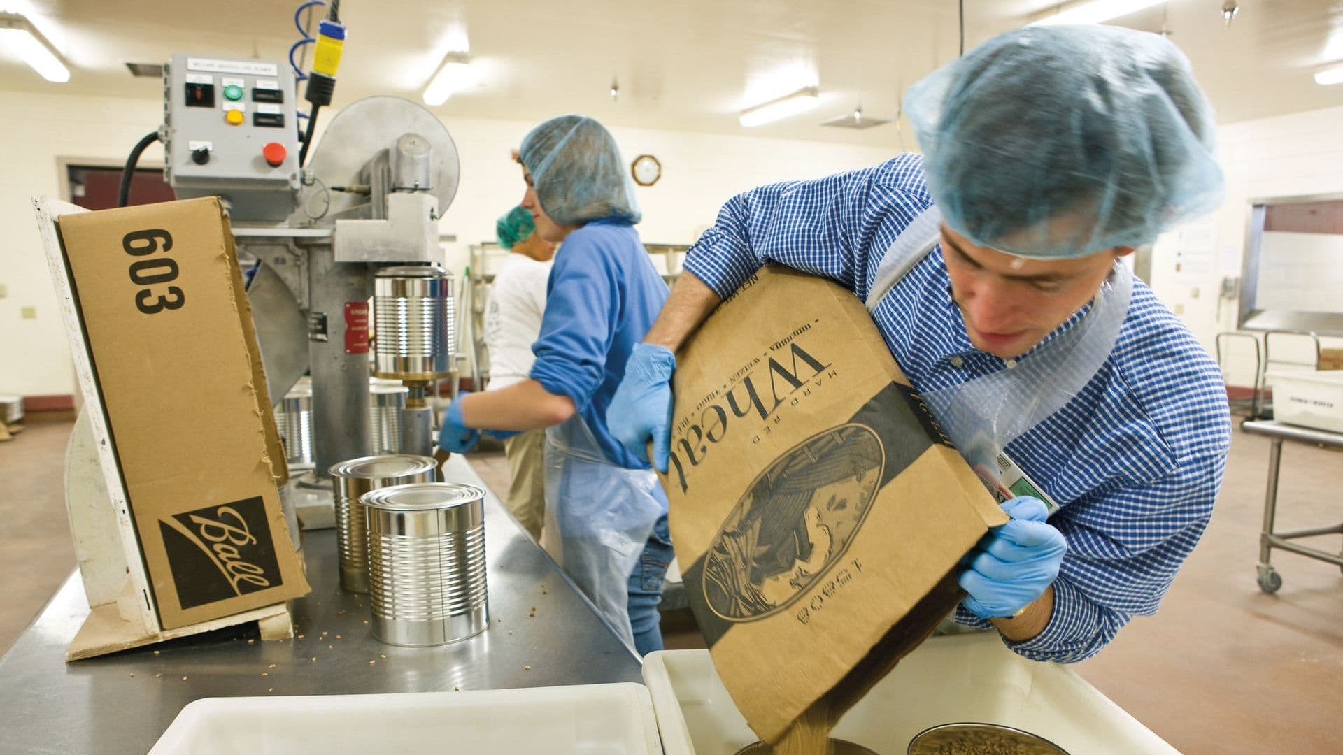 A worker pours wheat into #10 size cans at a Church facility. Image courtesy of The Church of Jesus Christ of Latter-day Saints.